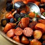 Butter braised carrots with thyme topped with fresh herbs and served in a pan