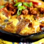 A hearty Easy Fajita Frittata in a cast iron skillet, topped with chorizo and green onions, showing a golden-brown crust and set on a colorful napkin.