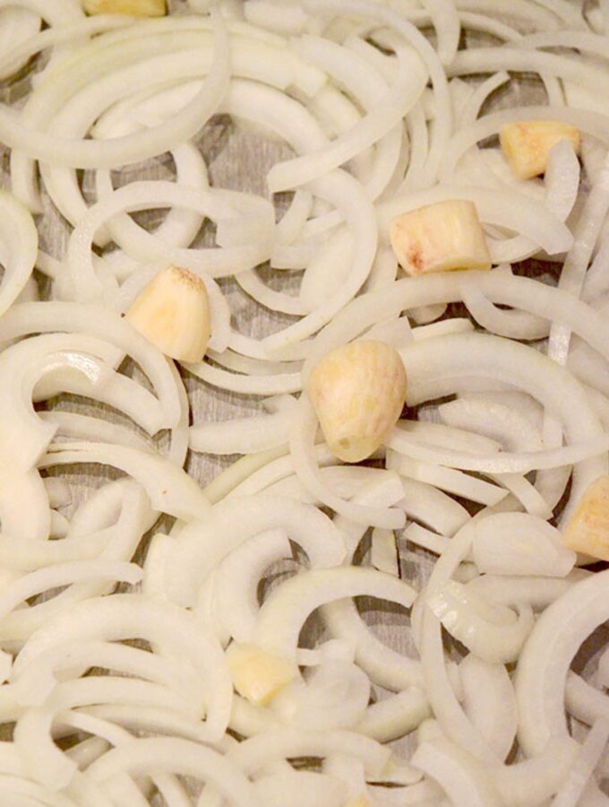 Step 1: Add the cut onions and garlic to the roasting pan.