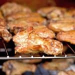 Golden-brown smoked chicken wings resting on a grill rack.