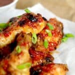 Thai sweet chili wings served on parchment paper and topped with scallions featured image