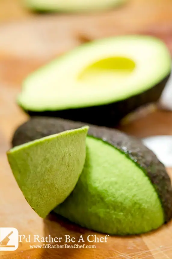 The fourth step in how to peel avocado is to slice the skin with a shallow cut and peel back the sections.