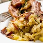 A detailed view of sautéed cabbage with crispy bacon and a fork on a white plate.