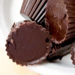 A top-down view of a white bowl filled with dark chocolate peanut butter cups. The focus is on the rich, dark chocolate, highlighting the texture and sheen of the peanut butter cups.