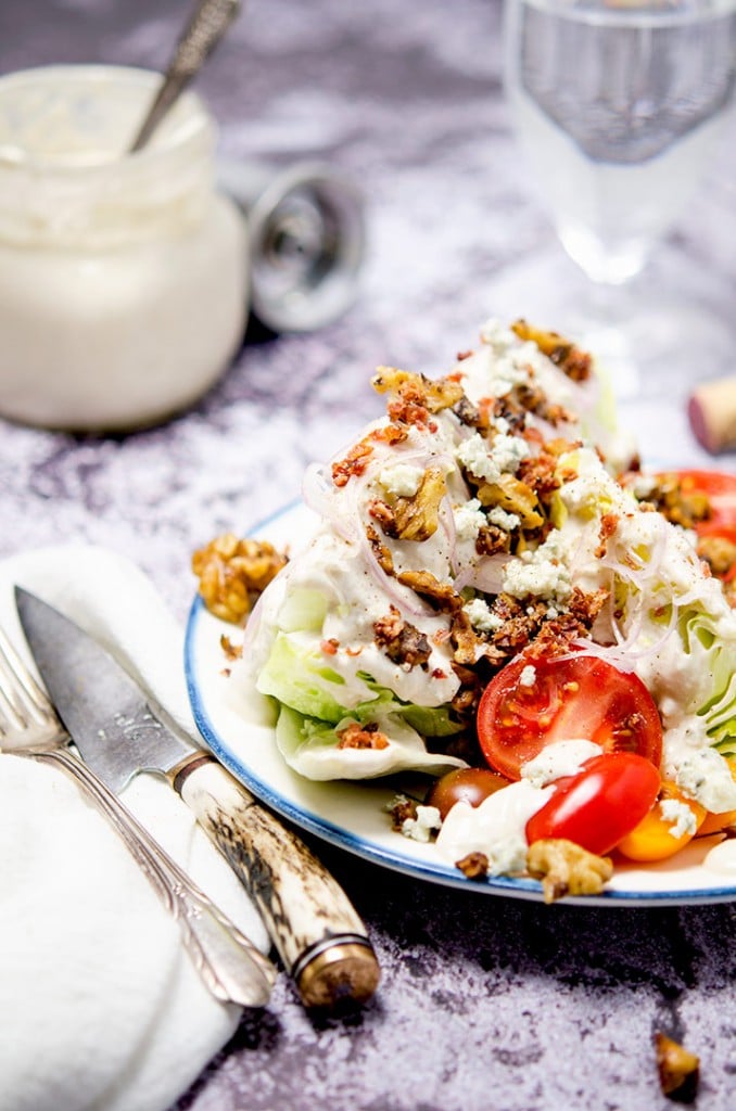The perfect iceberg wedge salad has blue cheese dressing, bacon bits, shallots, butter drunk walnuts and fresh tomatoes. Don't forget the blue cheese crumbles too!