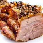 A close-up view of crispy pork belly, showcasing the golden, crunchy skin and juicy, tender meat seasoned with herbs and spices.
