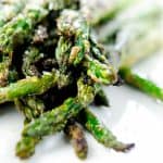 A close-up shot of grilled asparagus spears, charred to perfection, and topped with a light dusting of Parmesan cheese.