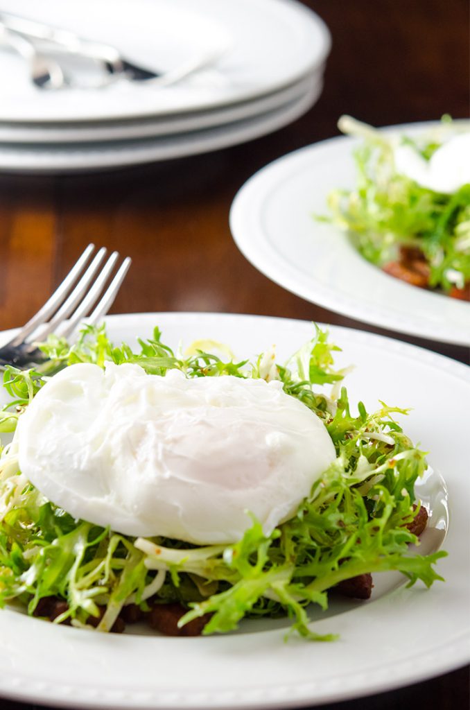 Frisee salad with a poached egg and bacon lardons, ready to eat.