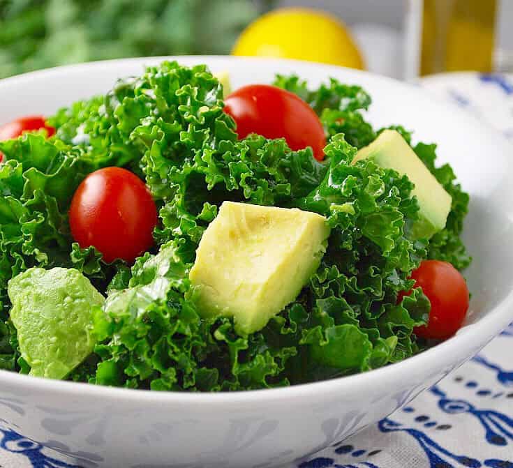 Marinated kale with avocado and tomatoes is the perfect salad to go with your low carb dinner recipes. Yum.