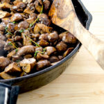 Pan full of sautéed mushrooms topped with fresh herbs