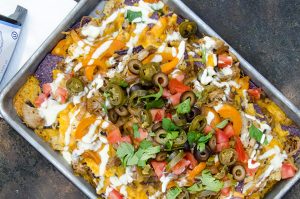 Fajita nachos are delicious when layered with cheese, pulled pork, onions, peppers and creme fraiche. Awesome.