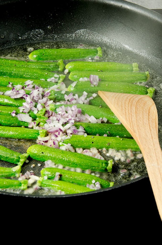 To make zucchini fries, we first add the zucchini to a pan to brown, then add in the remaining ingredients.