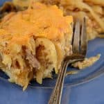 Baked pulled pork casserole with a cheesy golden top, served on a blue plate with a fork.