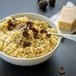 A close-up of a bowl of truffle risotto topped with shaved black truffles, highlighting the creamy texture and rich flavors.