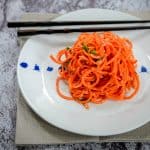 Featured image of Asian Carrot Salad served in a white bowl, with chopsticks placed on the side, set against a rustic backdrop.