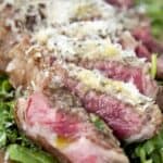 Close-up view of Bistecca Fiorentina steak slices topped with grated cheese, highlighting the juicy and tender texture.