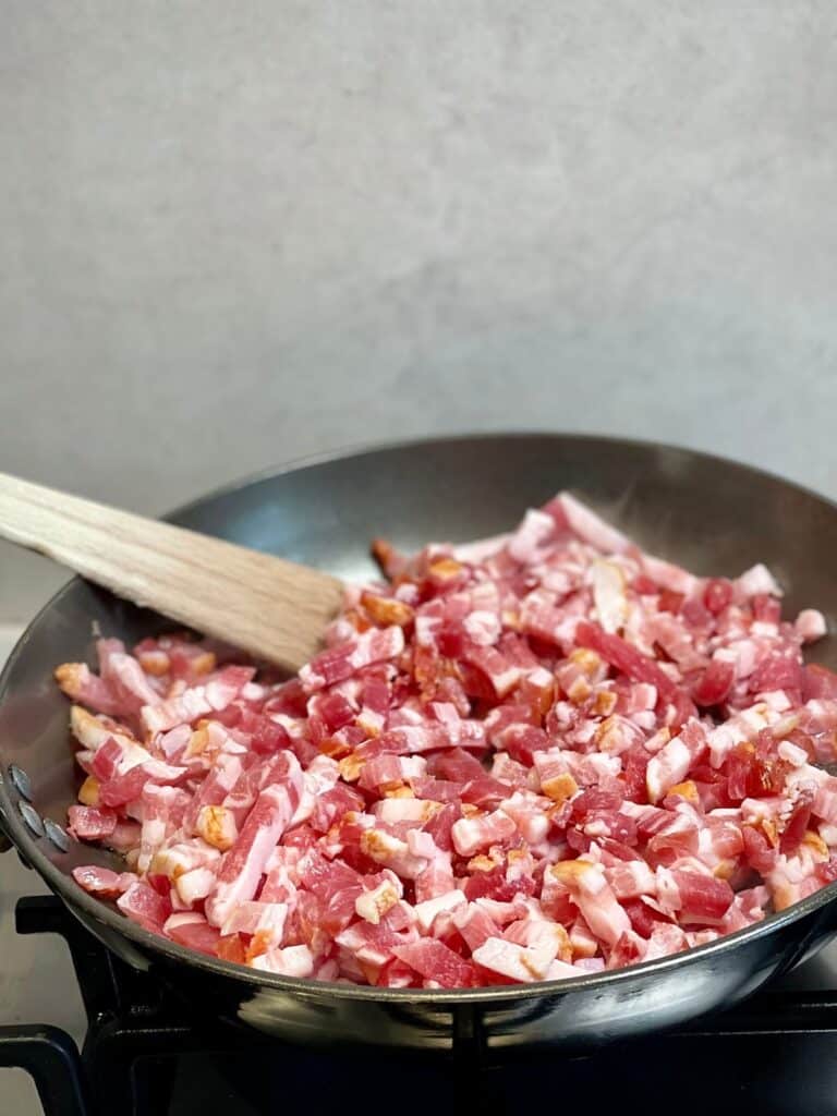 Chopped bacon being cooked in a pan for bacon bits