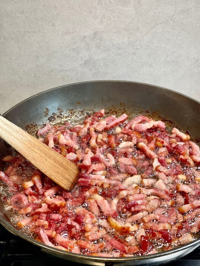 Chopped bacon cooking in a pan in preparation for bacon bits