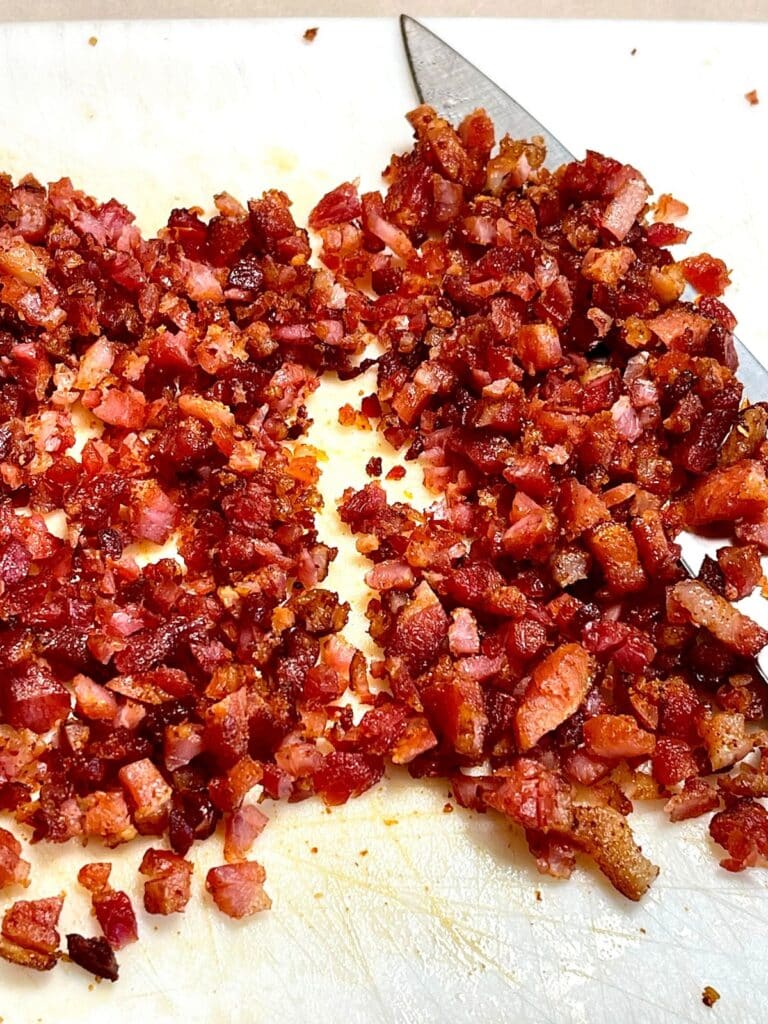 Tray full of homemade bacon bits topped with various spices and seasonings