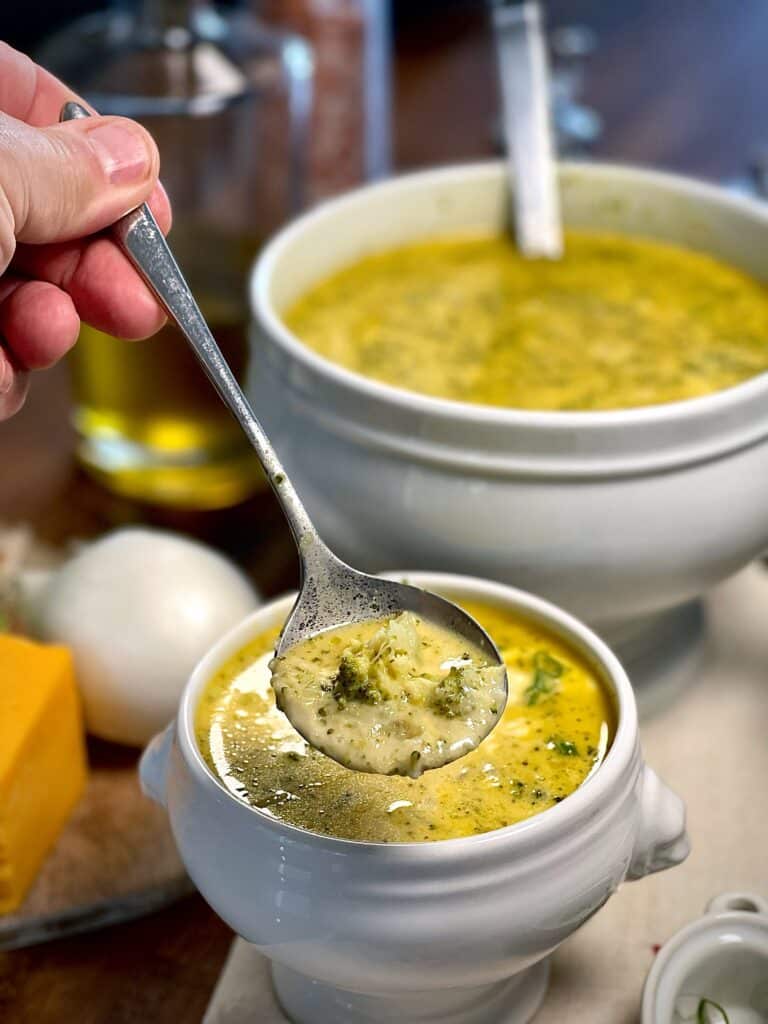 Image of a spoon filled with broccoli cheese soup.