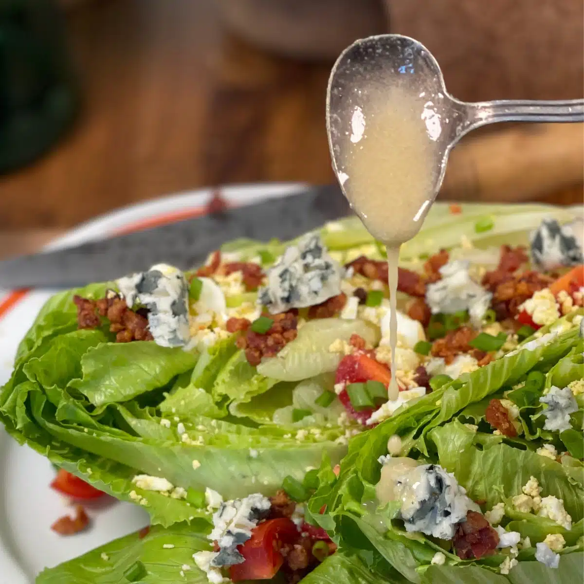 Ladle of hot bacon salad dressing drizzling over a sald