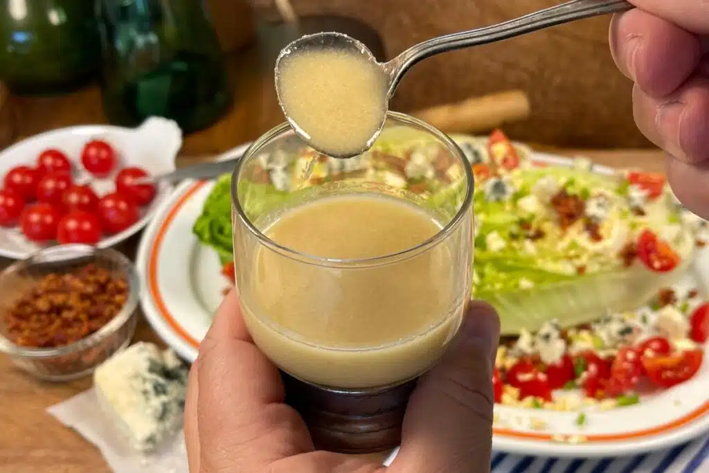 Ladleful of hot bacon salad dressing over a small pot of dressing