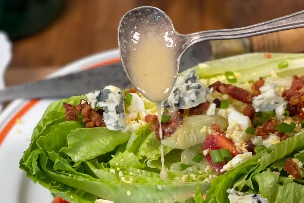 Hot bacon salad dressing drizzling over a salad