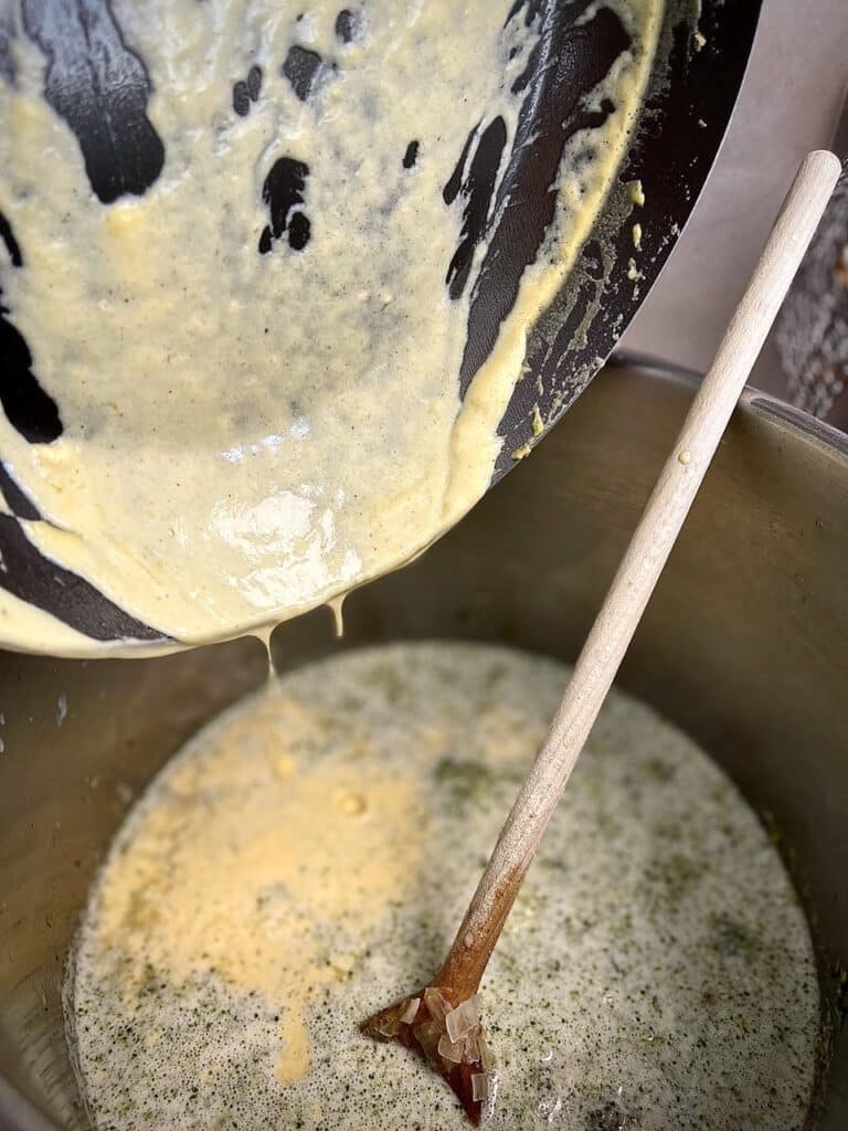 Adding the cheese to the blended broccoli soup.