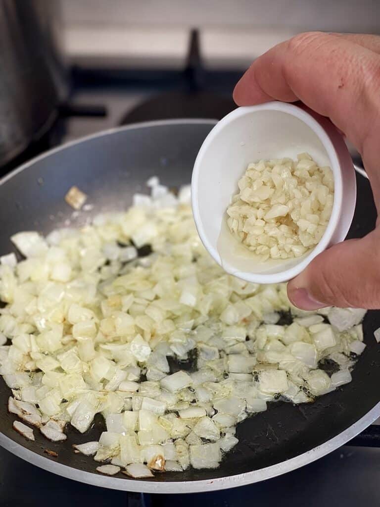 Adding garlic to a frying pan.
