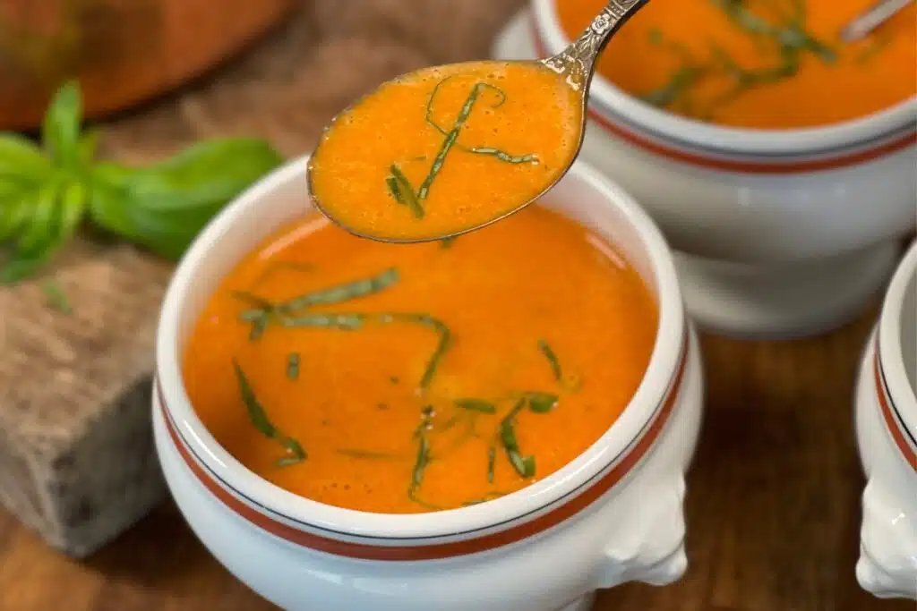 Spoonful of roasted red pepper soup topped with fresh herbs