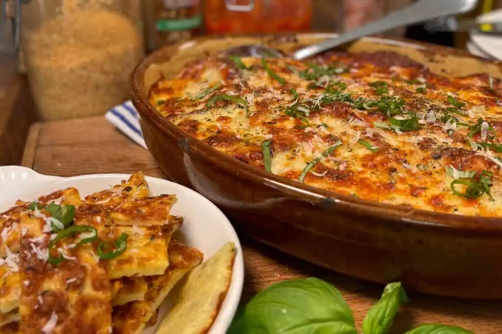 Close up of baking dish full of keto eggplant Parmesan topped with fresh herbs