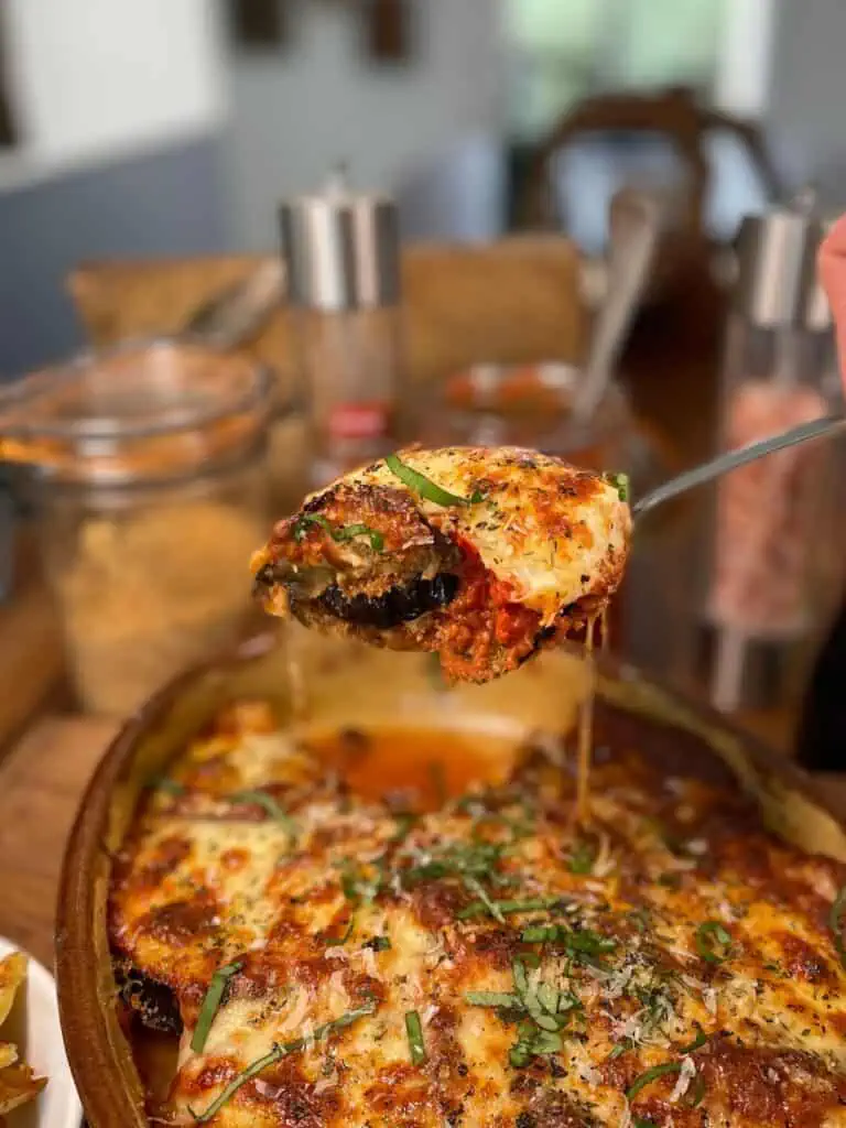 Spoonful of keto eggplant Parmesan garnished with herbs