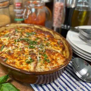 Keto eggplant Parmesan in a baking topped with herbs and fresh Parmesan featured image
