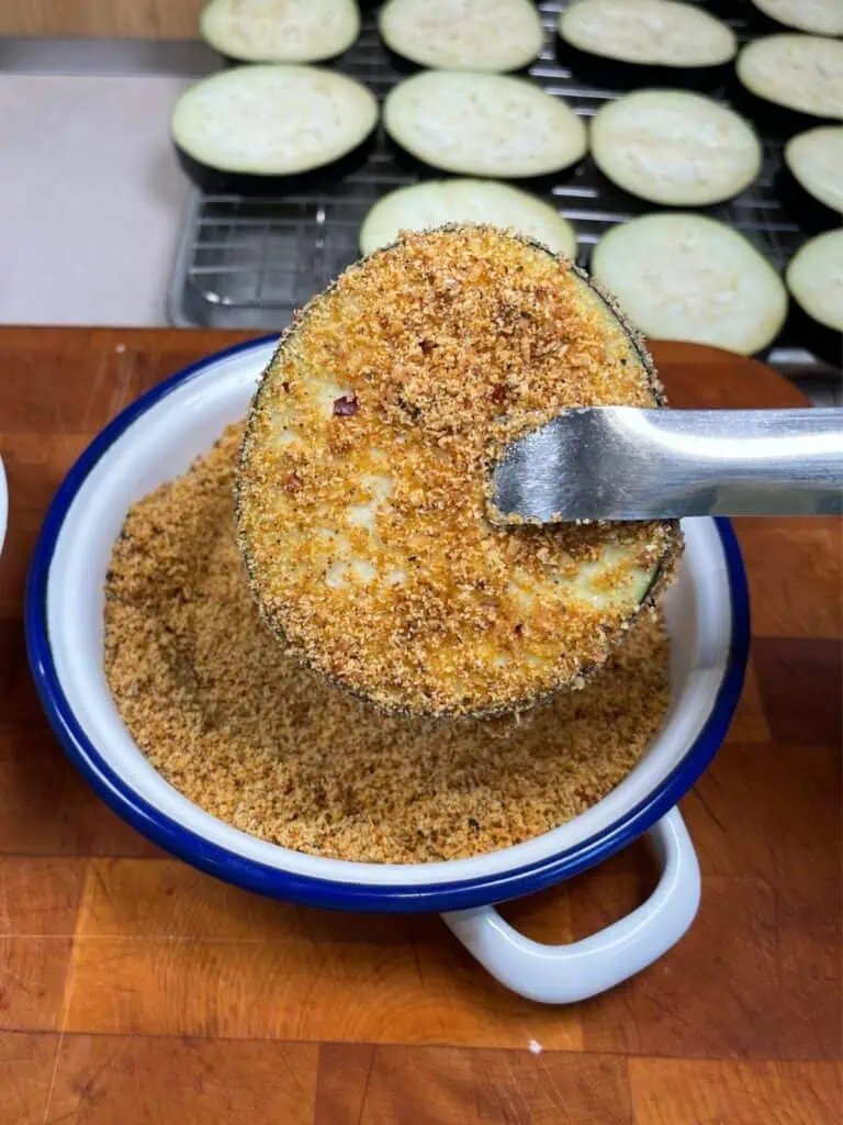 Eggplant being dipped into low carb bread crumbs