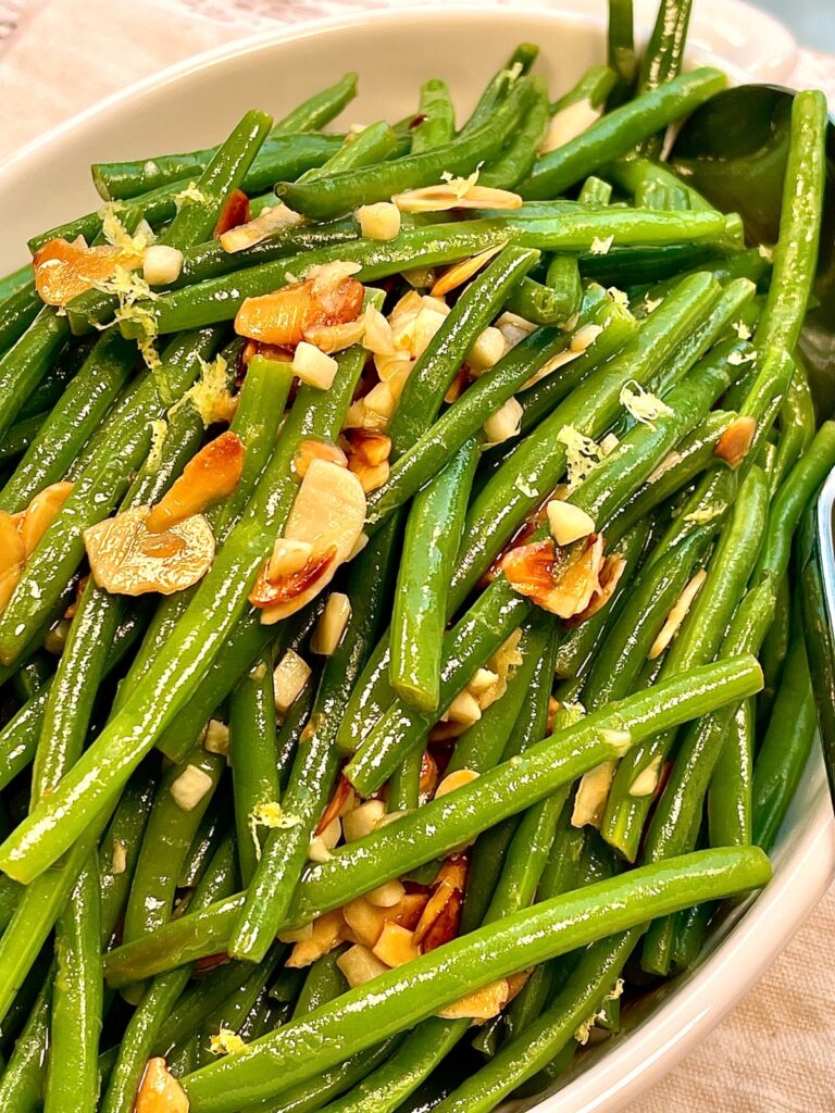 Close up of French haricots verts topped with nuts and garlic