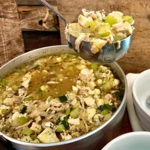 Easy leftover rotisserie chicken soup served in a ladle suspended over pot of soup featured image