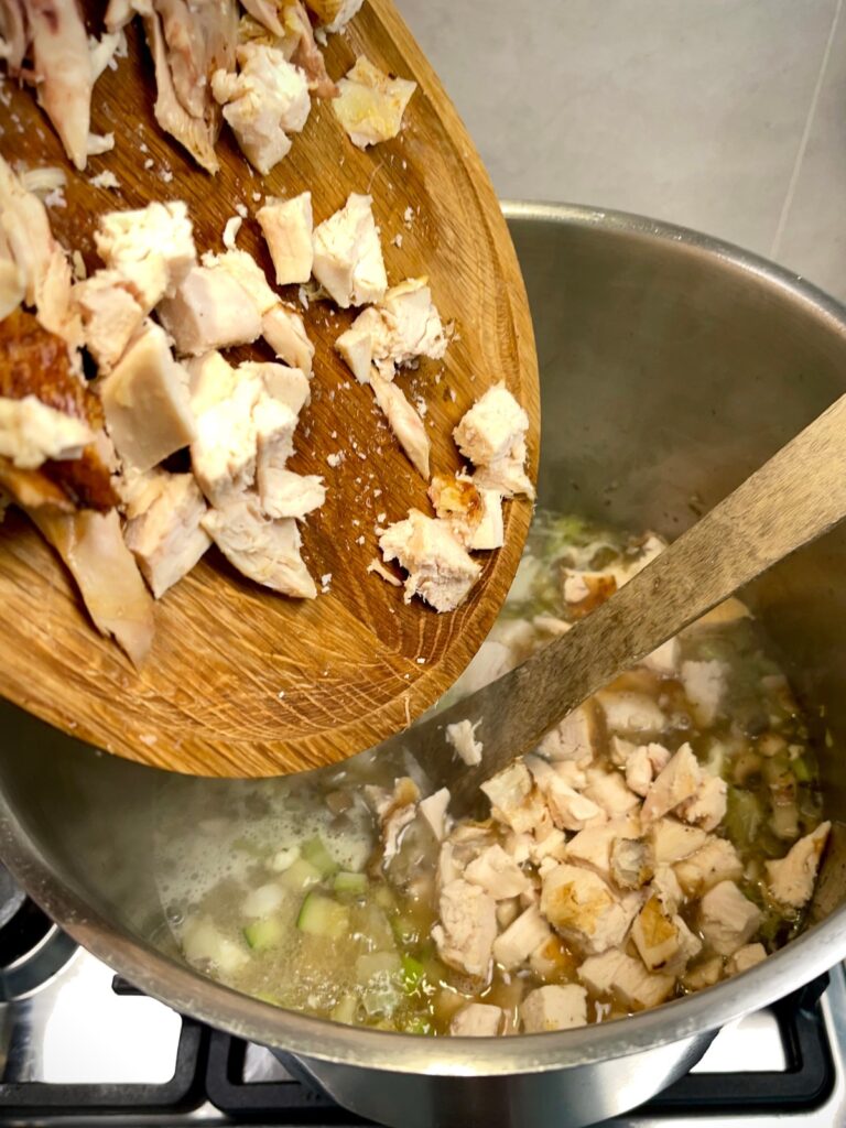 Chicken being added to the soup pot