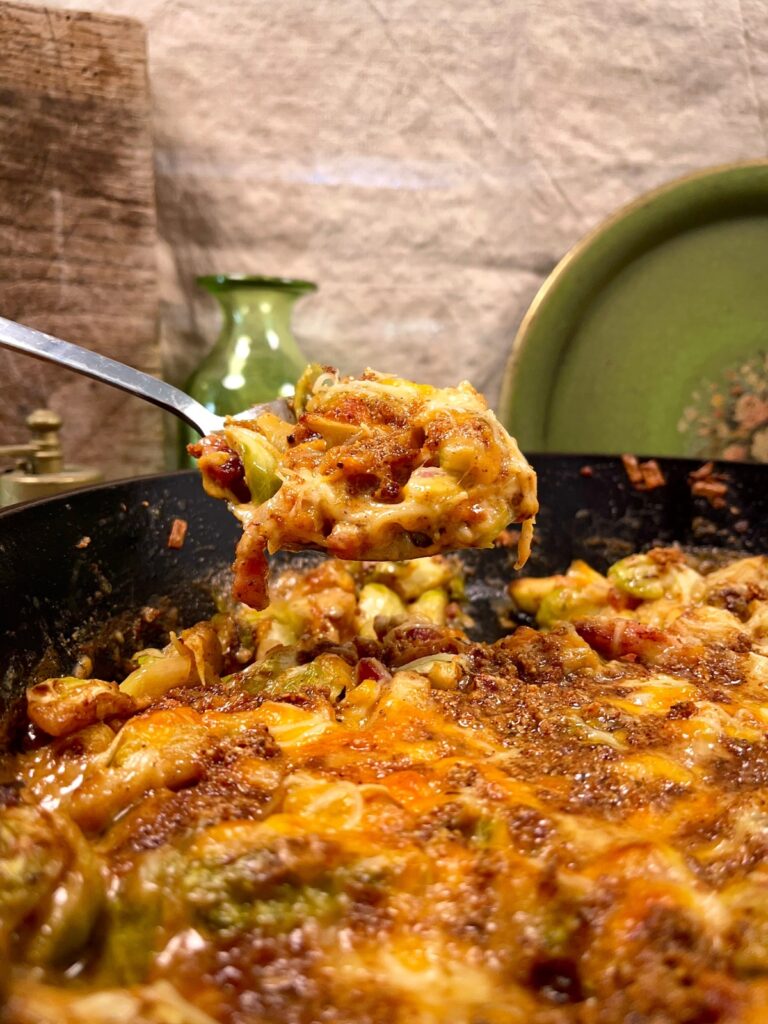 Spoonful of cheesy brussel sprout casserole suspended over pan
