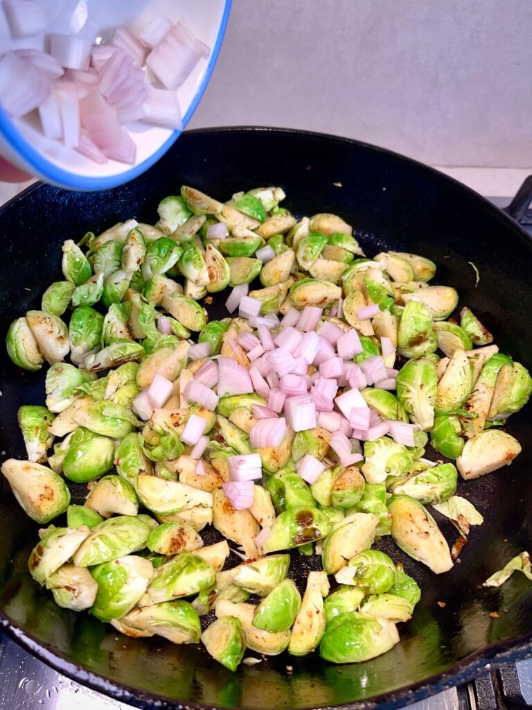 Ingredients cooking in a pan for cheesy Brussels sprout casserole