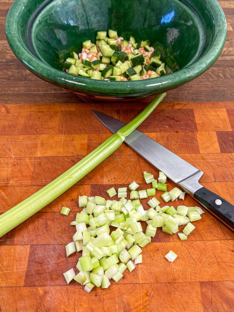 Chopped celery on a cutting board for preparation of keto shrimp salad