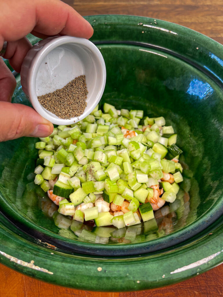 Ingredients being mixed in a bowl in preparation for shrimp salad