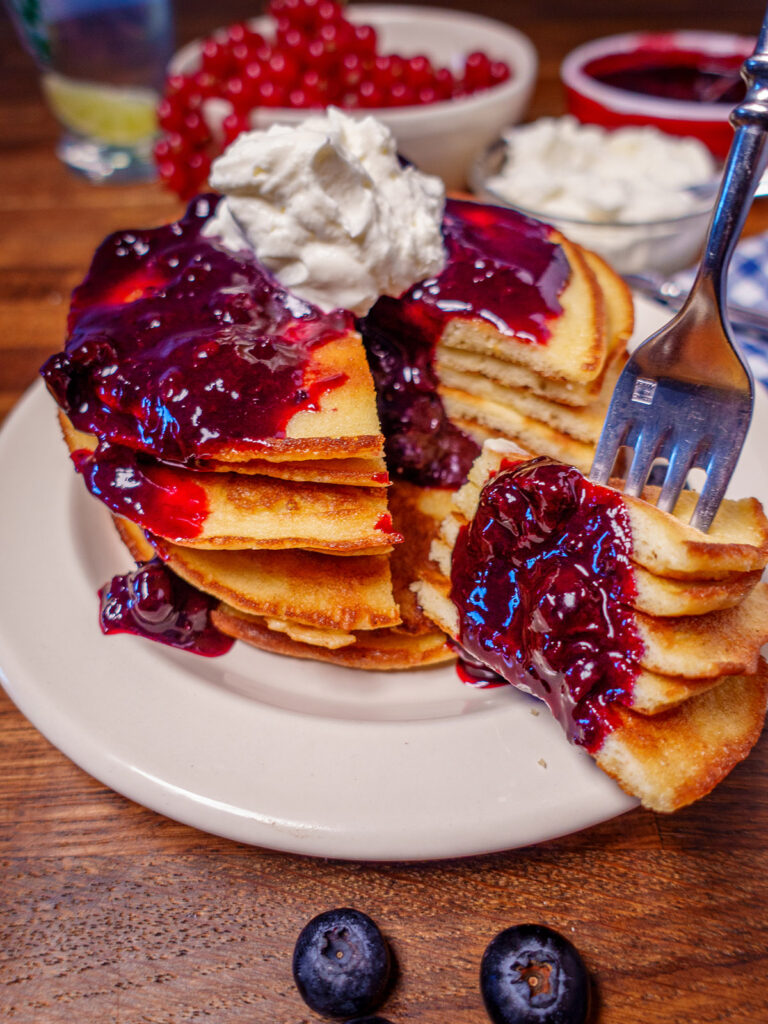 Plate of keto pancakes topped with blueberry sauce and whipped cream