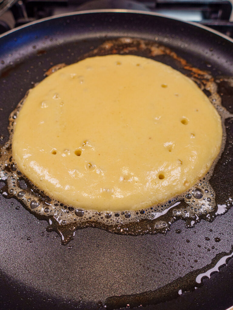 Keto pancake batter on a pan cooking