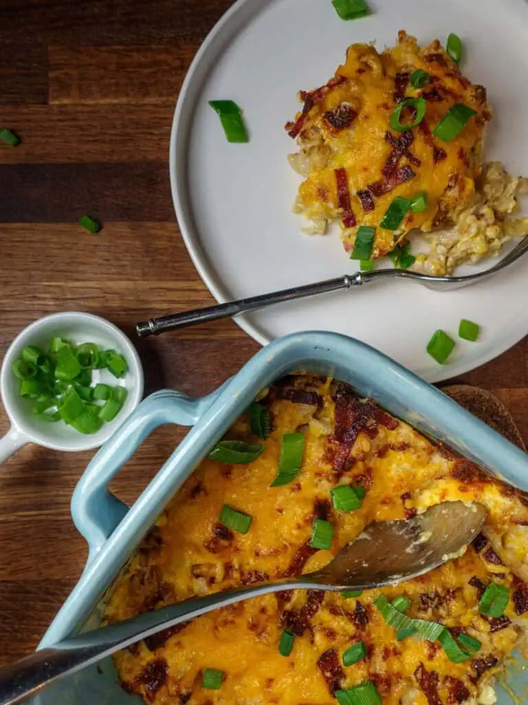 Plate and tray of loaded cauliflower bake topped with scallions