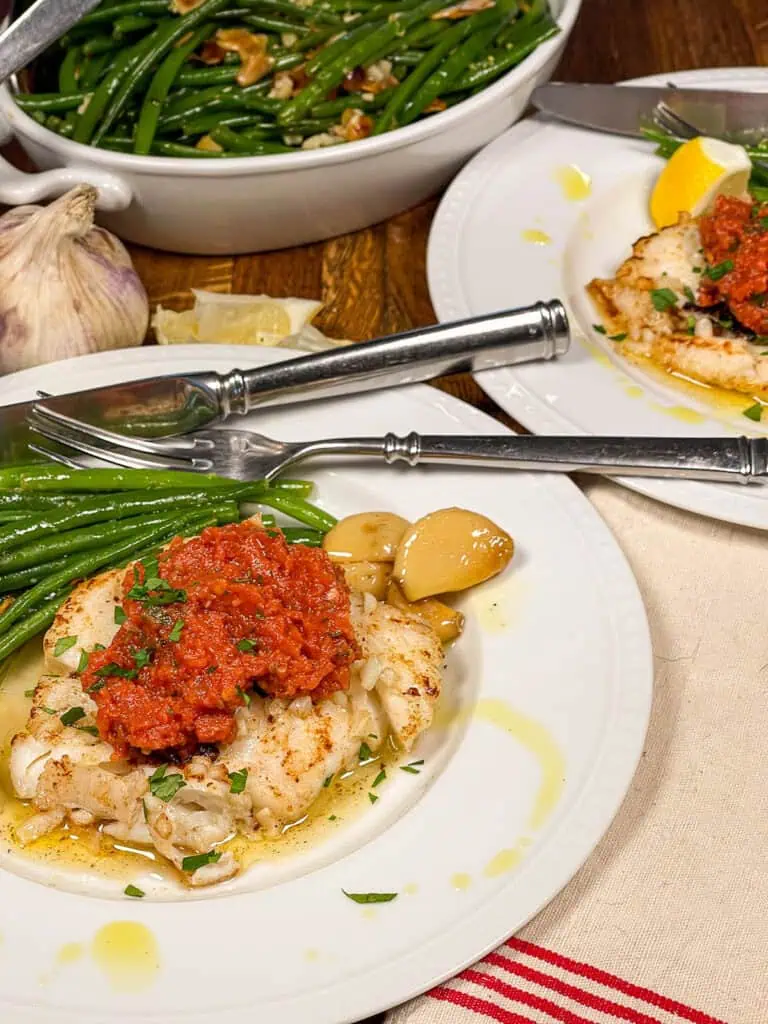 pan seared cod with fresh tomato coulis on a white plate