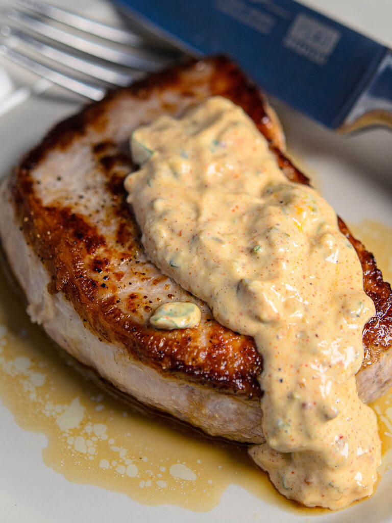 Pork chop garnished in low carb remoulade sauce close up