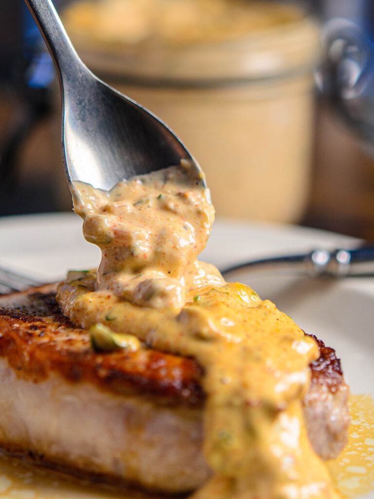 Pork chop garnished in low carb remoulade sauce close up