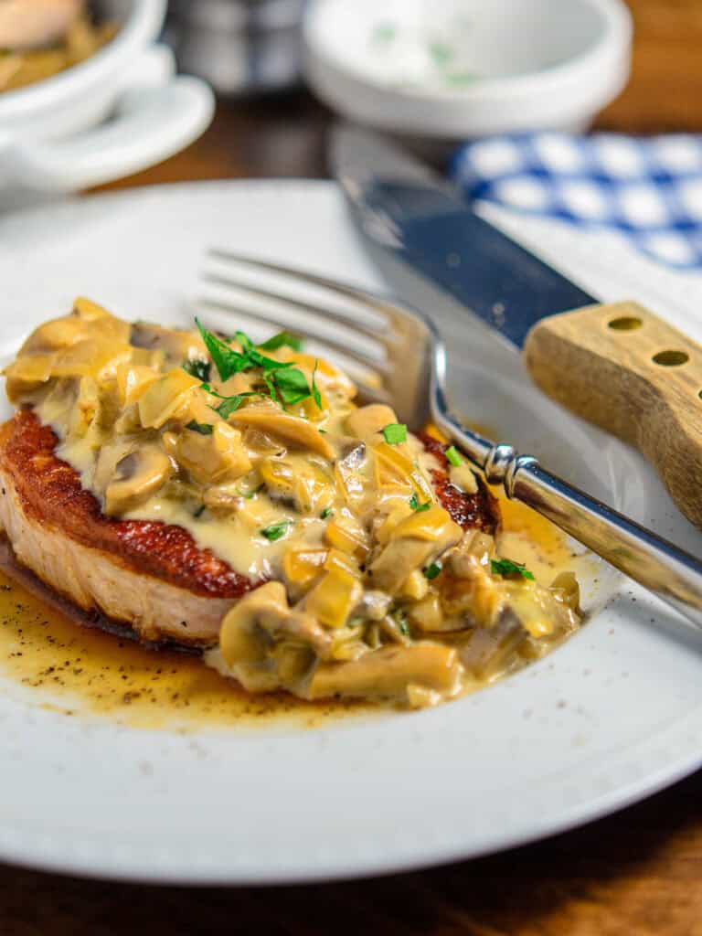 Plate of smothered pork chops topped with minced basil