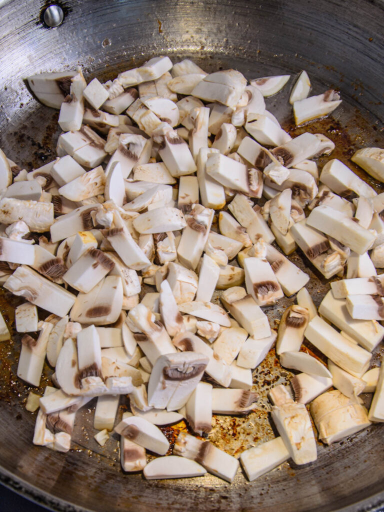 Pan full of uncooked mushrooms for smothered pork chops