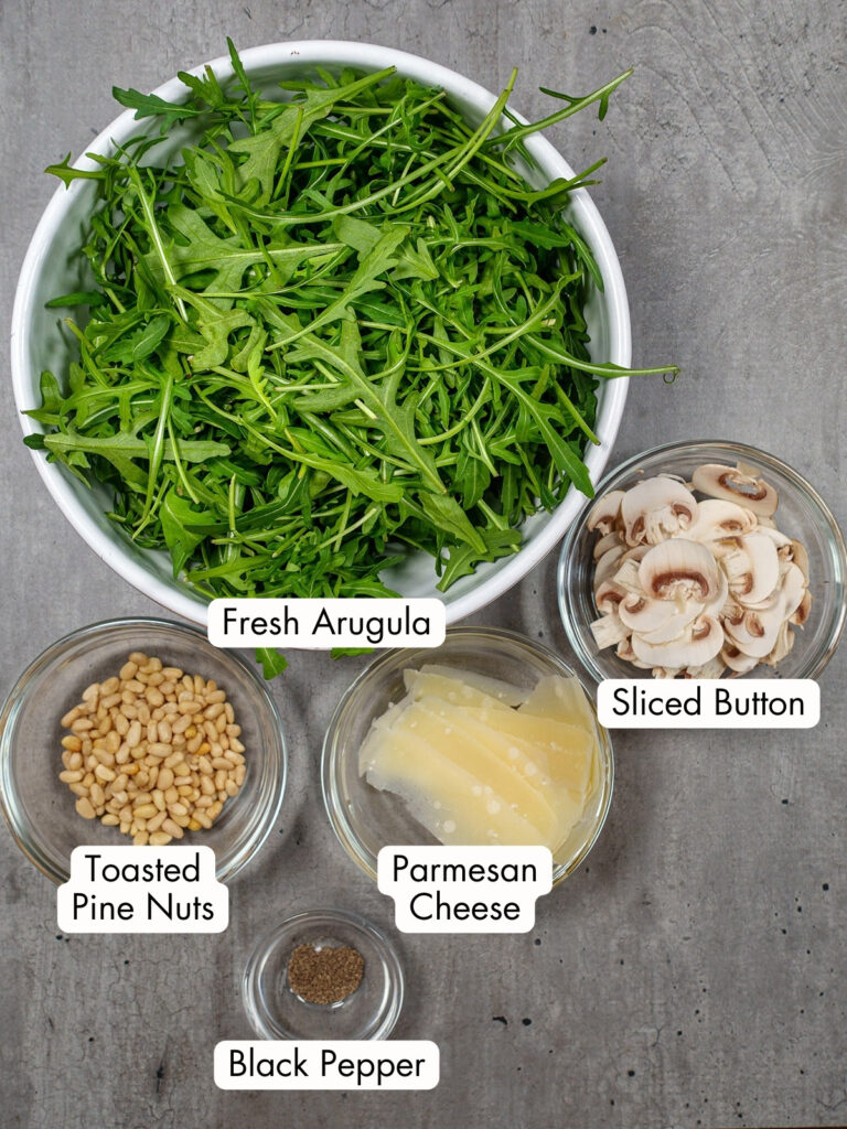 Arugula salad with mushrooms ingredients image with text overlaid on each ingredient